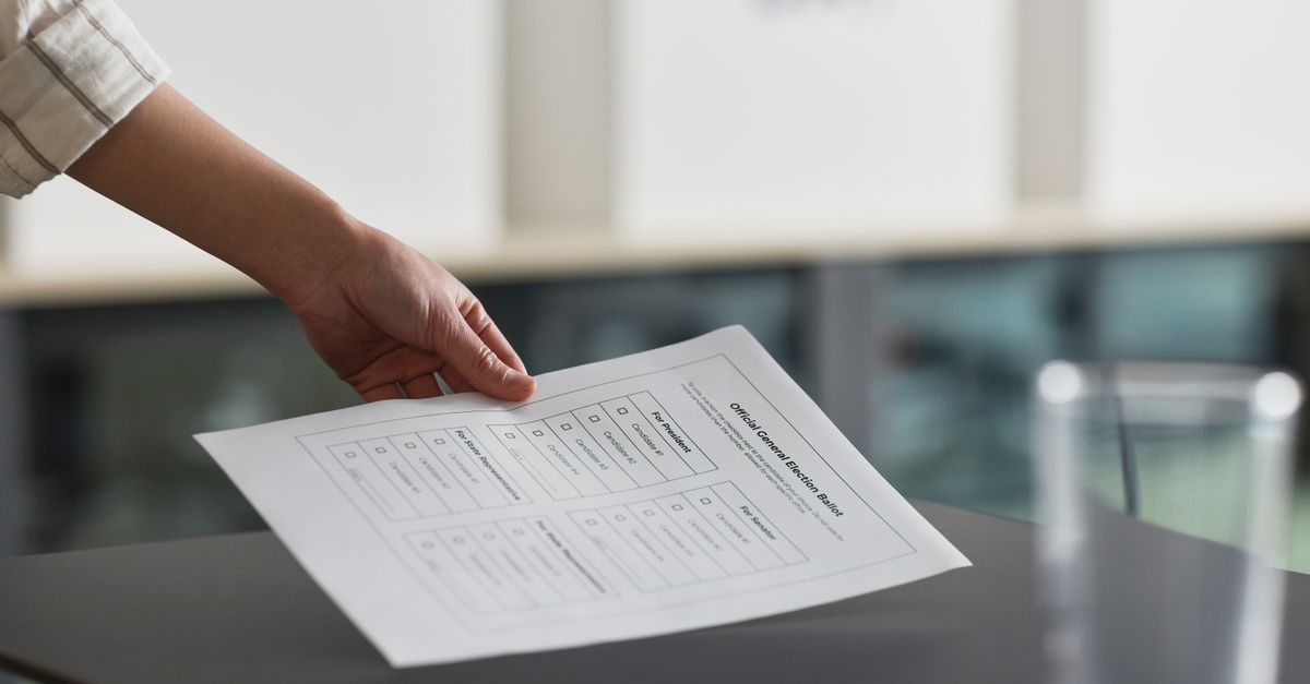 Close-up of a hand holding a ballot paper indoors, symbolizing democracy and civil rights.
